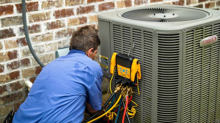 Technician connecting service gauges to an outdoor condenser