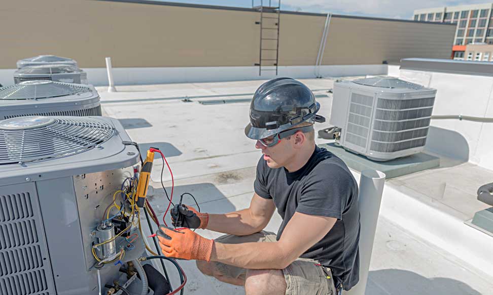 HVAC technician diagnosing rooftop cooling equipment