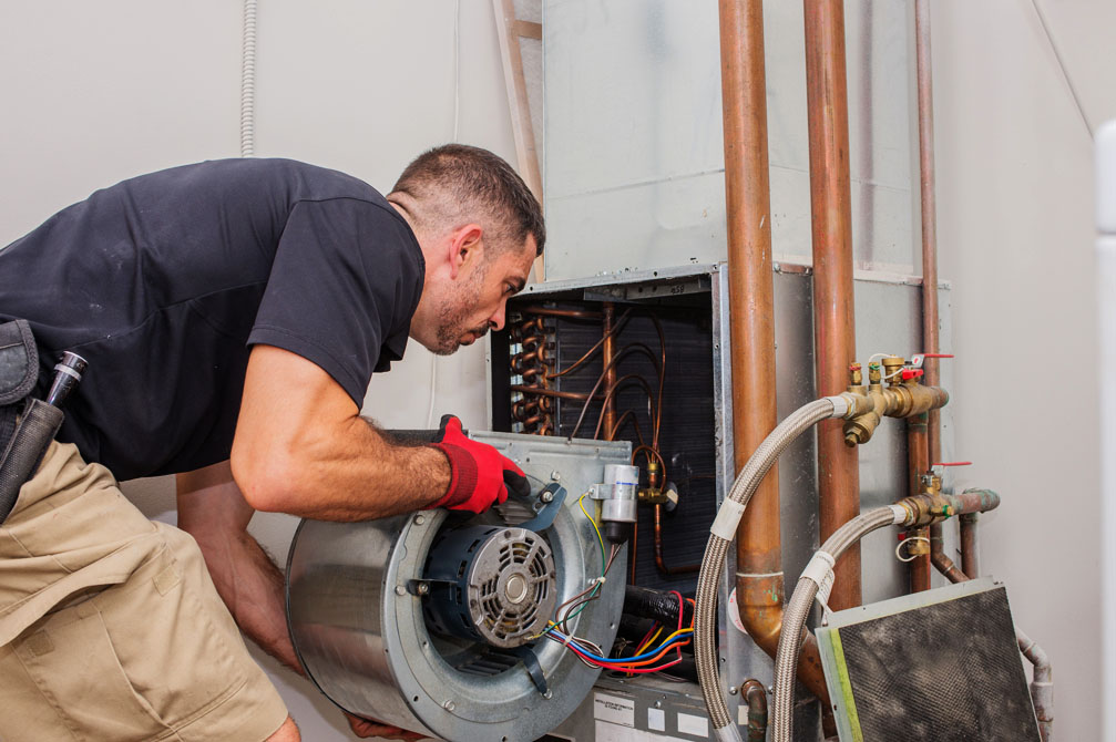 Technician inspecting a furnace blower assembly