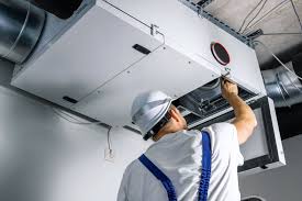 Technician servicing a ceiling-mounted HVAC air handler